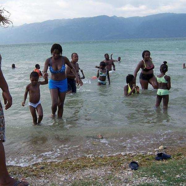 Familles se baignant dans les eaux peu profondes du lac Azuei, montagnes à l'horizon