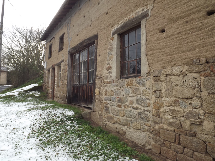 Corps de ferme en pisé plus que centenaire, en Auvergne, dont les lits de terre damée restent visibles